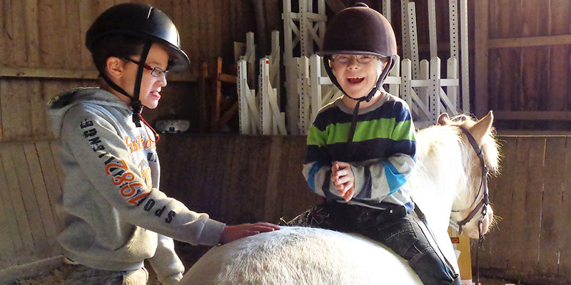 Illustration des activités possibles au SESSAD de l'Unapei de l'Oise. Ici deux enfants sont heureux de monter à cheval.