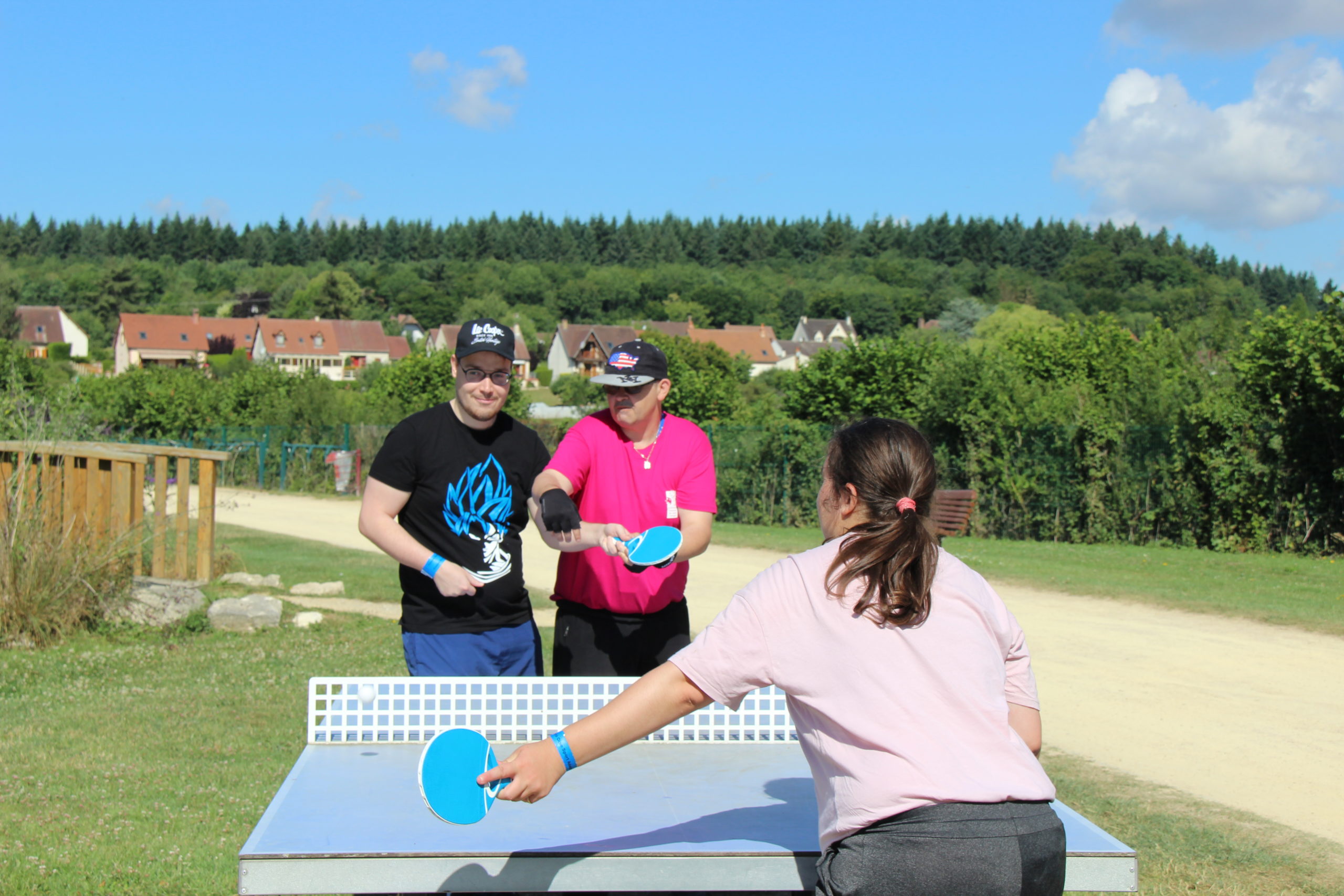 Deux jeunes en situation de handicap joue aux tennis de table, aidés par un bénévole de la Journée Départementale de Sport Adapté