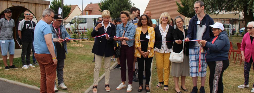 La présidente de l'Unapei de l'Oise et la représentante de la Mairie de Bailleul-sur-Thérain coupent le ruban pour inaugurer le jardin sensori-moteur, entourées de professionnels, administrateurs et résidents de l'Association.