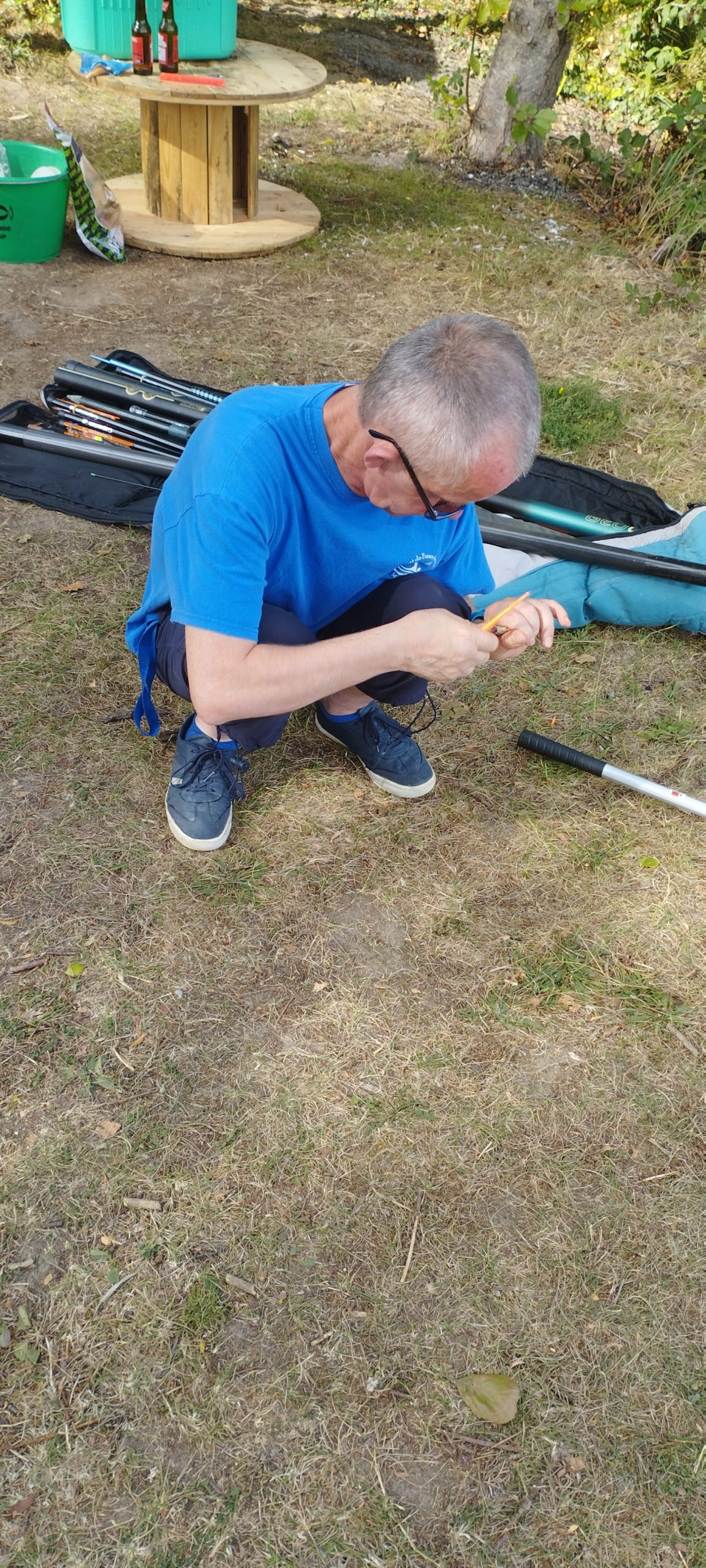 un résident d'Halatte pose un appât sur sa canne à pêche lors d'une sortie estivale