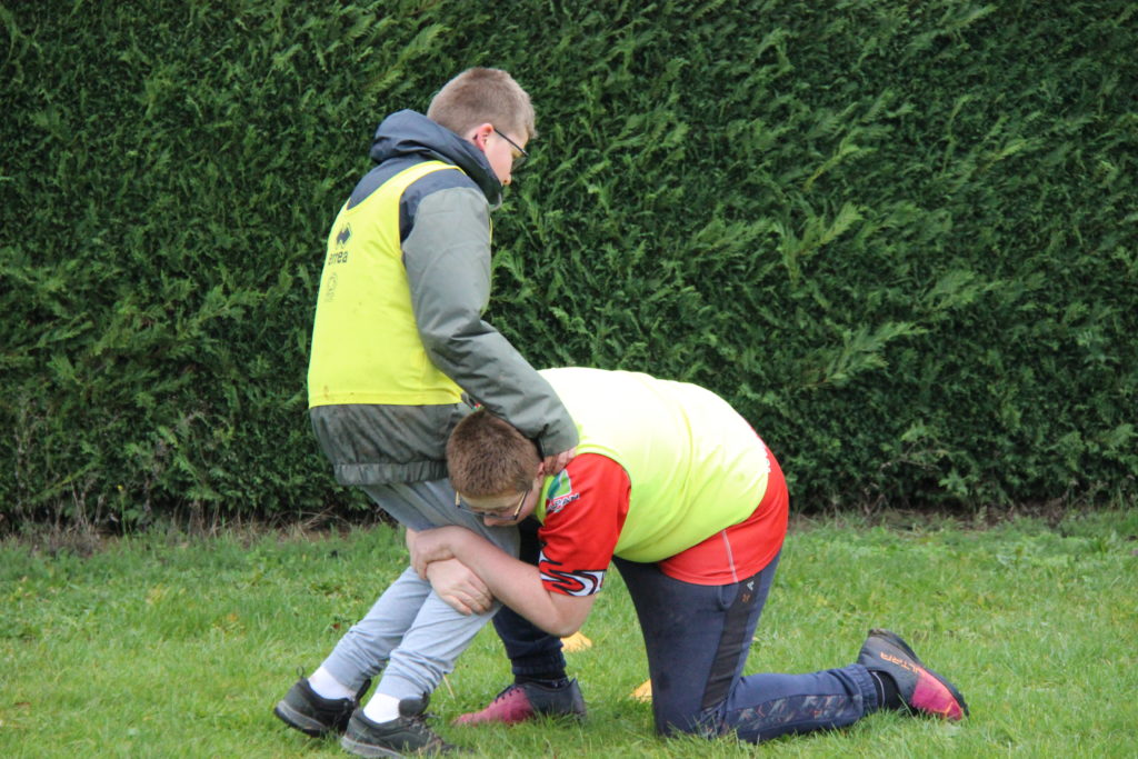 Deux jeunes garçons s'entrainement au plaquage de rugby.