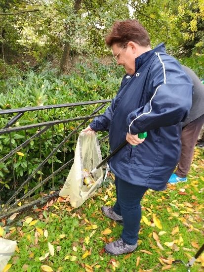 Une résidente au FAM et bénévole au GEM de Beauvais ramasse des déchets dans un parc.