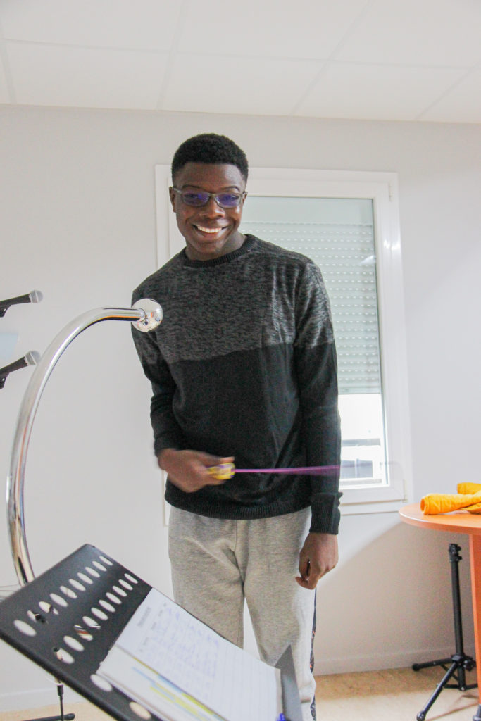 Joshua, jeune accueilli à l'IME Les Etoiles, utilise une baguette pour jouer au BAO PAO avec le sourire.