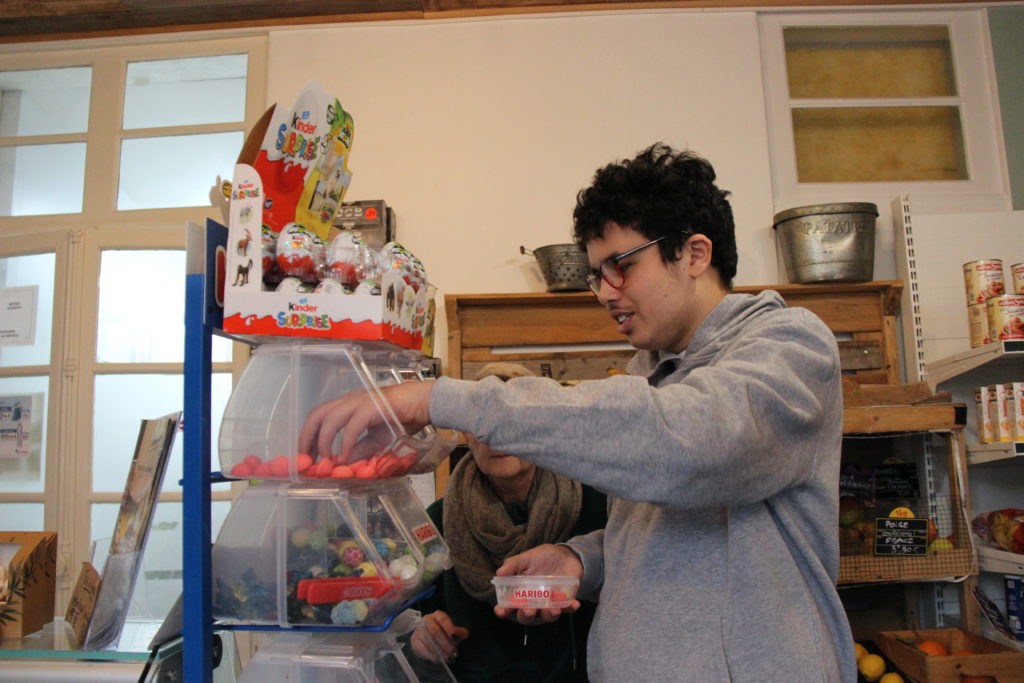 Yanis conditionne les bonbons en petits sachets : sa mission préférée de ce projet d'inclusion au sein de l'épicerie du village.