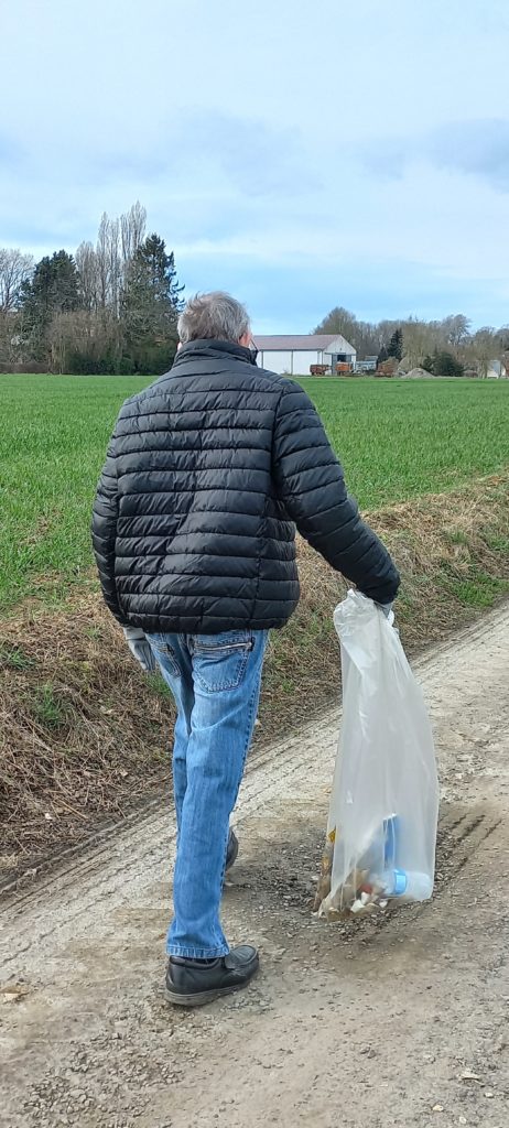 un résident porte un sac poubelle rempli de déchets