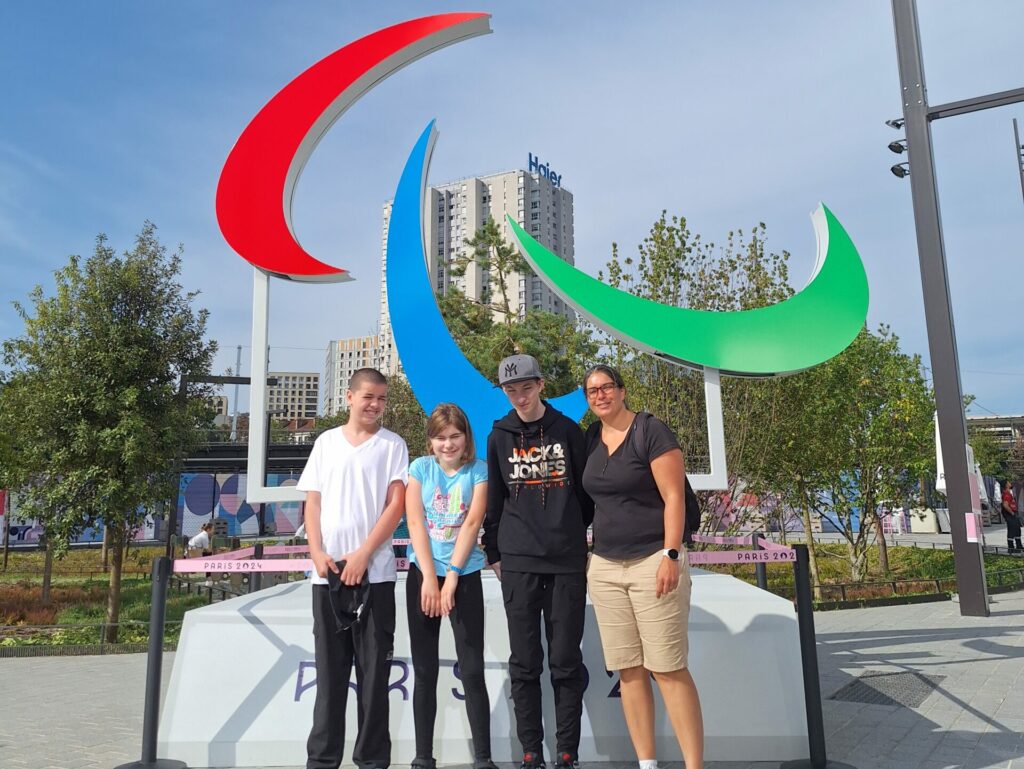 Jeunes et professionnels de l'IME Les Papillons Blancs posent sous les agitos de Paris 2024.