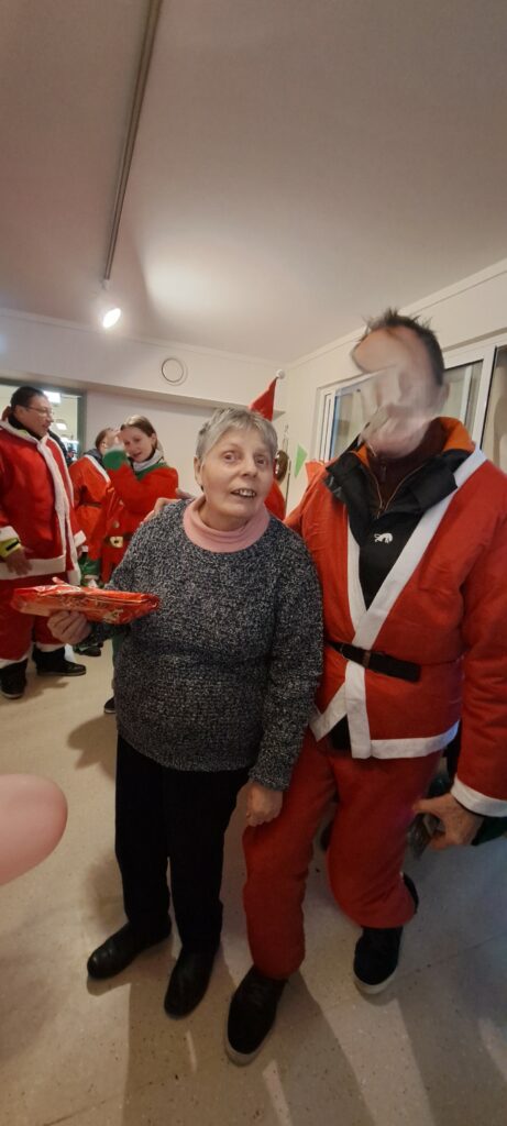 Un membre de l'association Joe Bar 60 déguisé en Père Noël offre un cadeau à une résidente des 4 Tilleuls